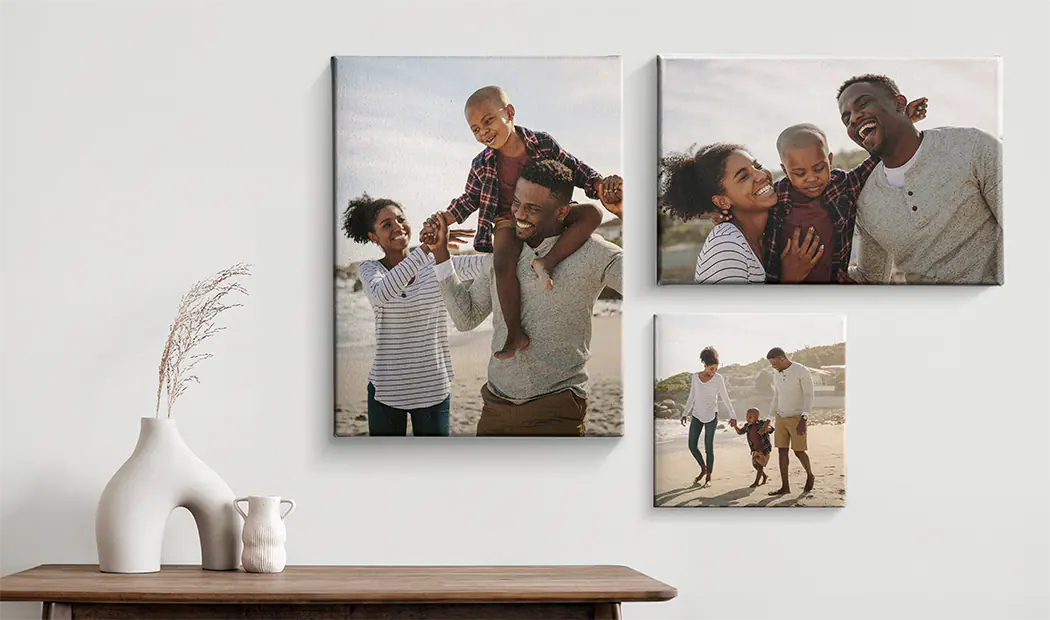Canvas prints of a family on a wall above a side table